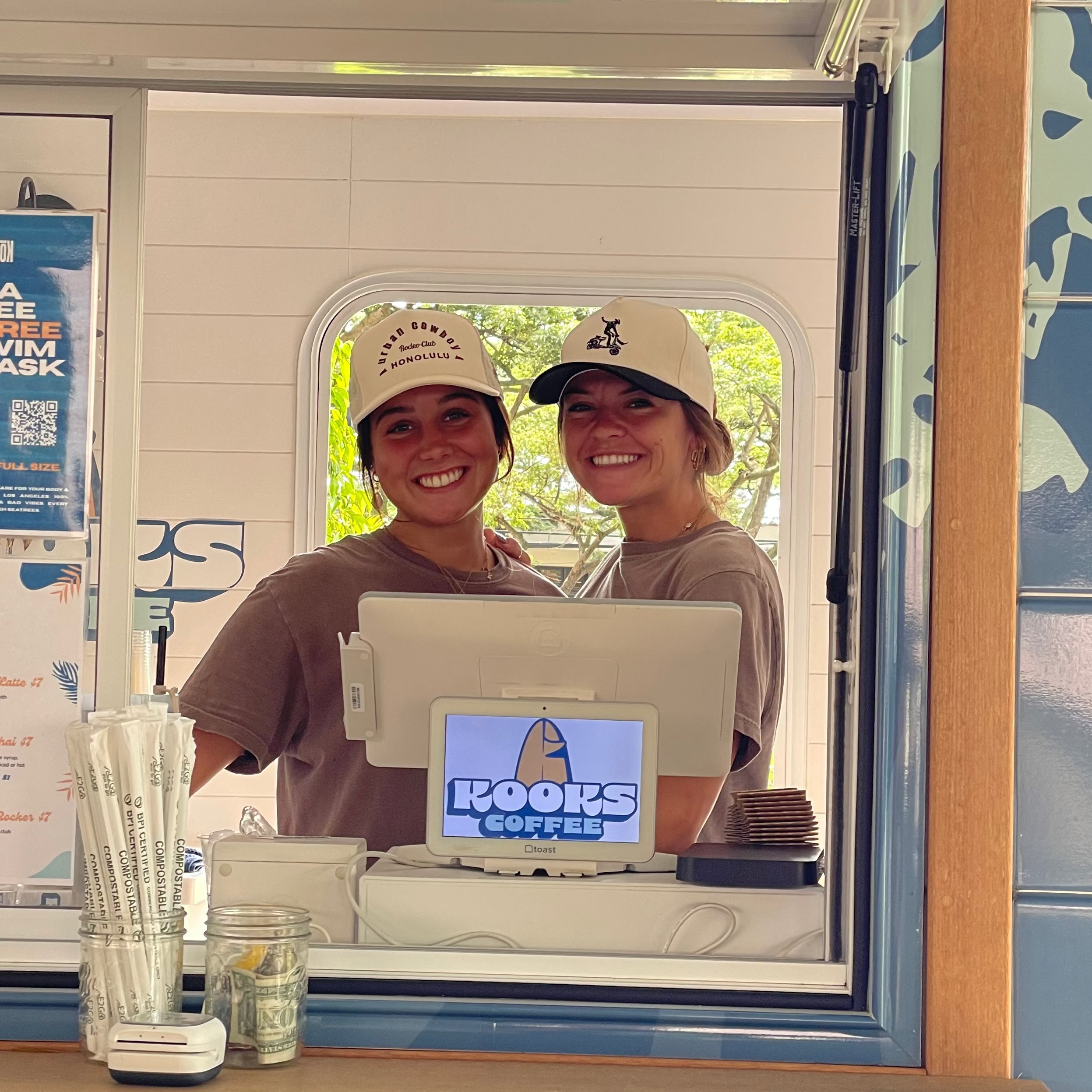 Two people inside a food truck with a laptop displaying 'Kool-Aid' branding.