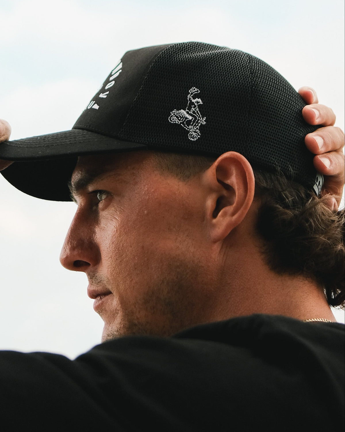 Urban Cowboy Co. The Outlaw black mesh snapback hat with white embroidery worn by a man in profile view